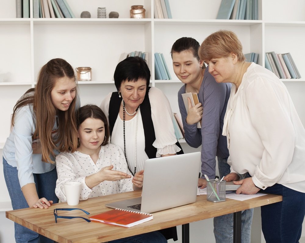 Trainee teachers studying together around a laptop