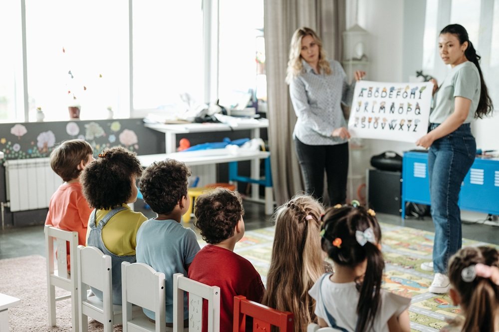 Teachers showing a chart to seated children